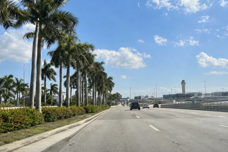 A palm-lined approach road with the MIA control tower ahead