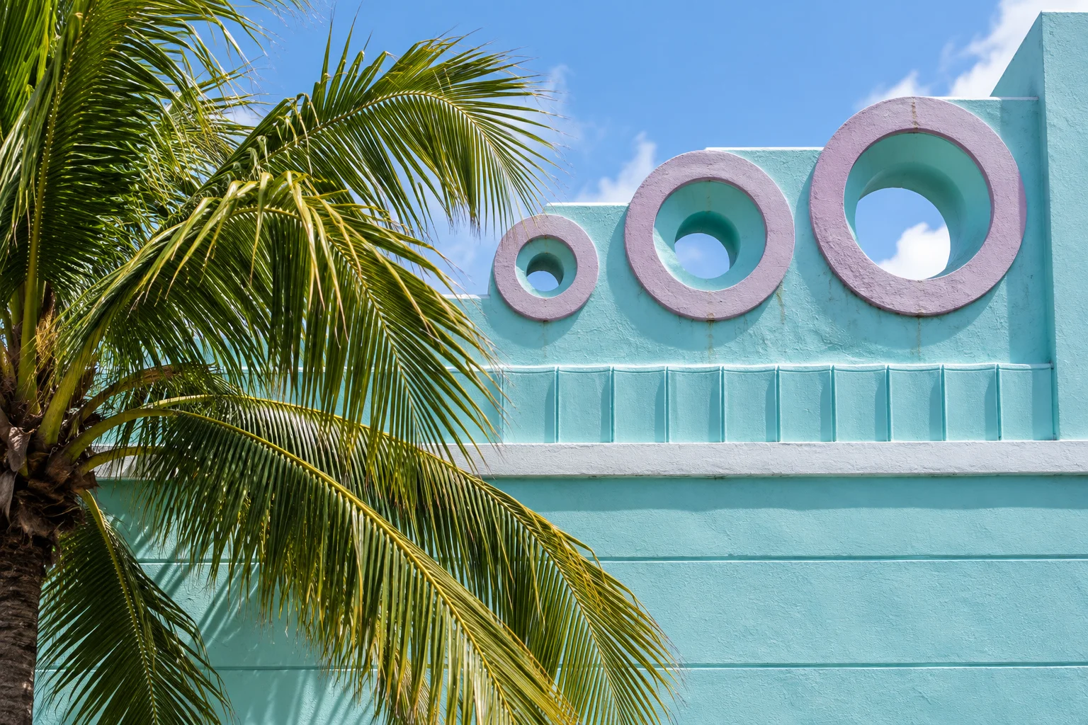 Palm tree beside a turquoise art-deco facade in South Beach